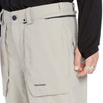 Volcom Men's Roan Shell Pant 2025 - A pair of khaki-colored snow pants with a zippered pocket on the thigh and adjustable Velcro straps at the waist.