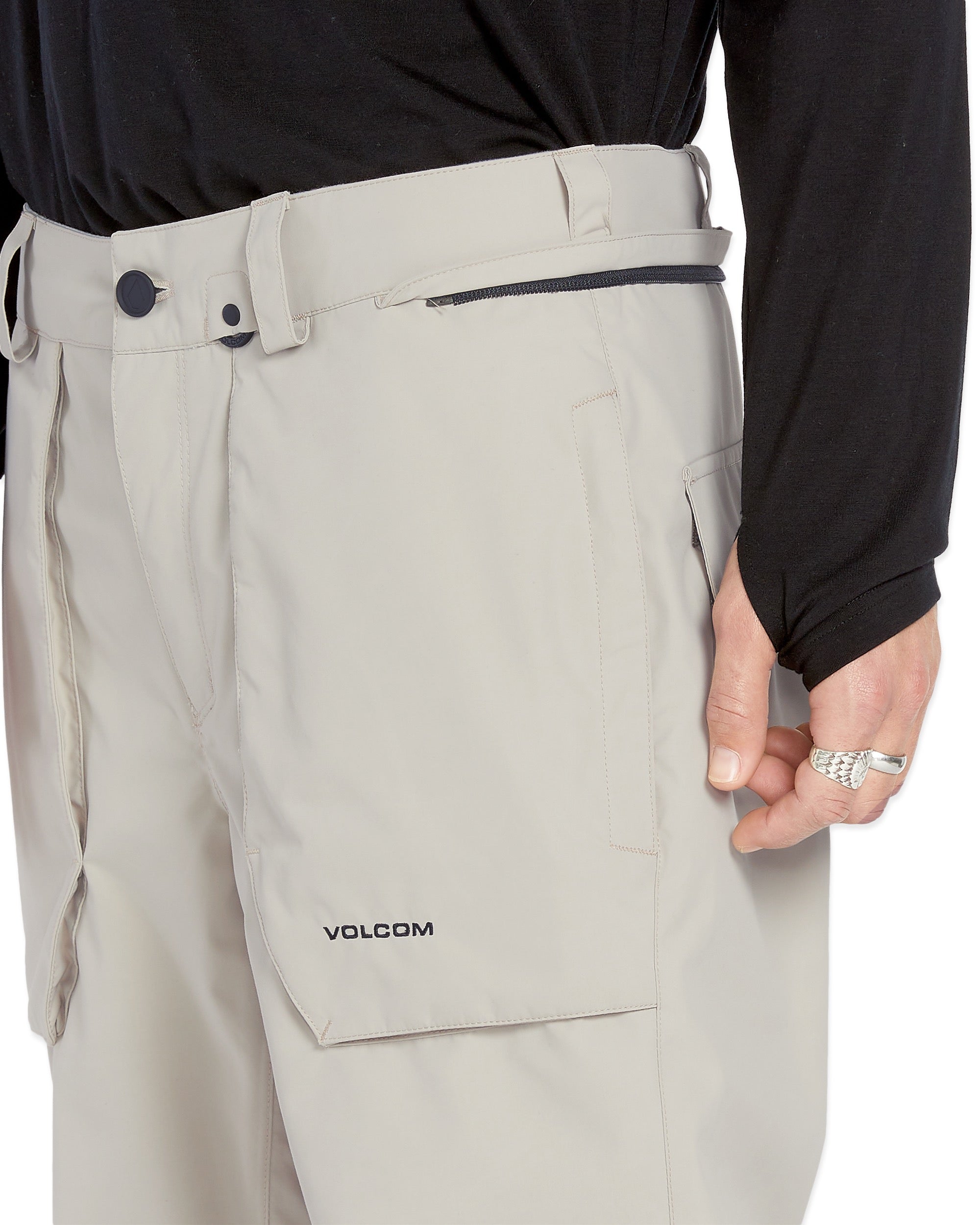 Volcom Men's Roan Shell Pant 2025 - A pair of khaki-colored snow pants with a zippered pocket on the thigh and adjustable Velcro straps at the waist.