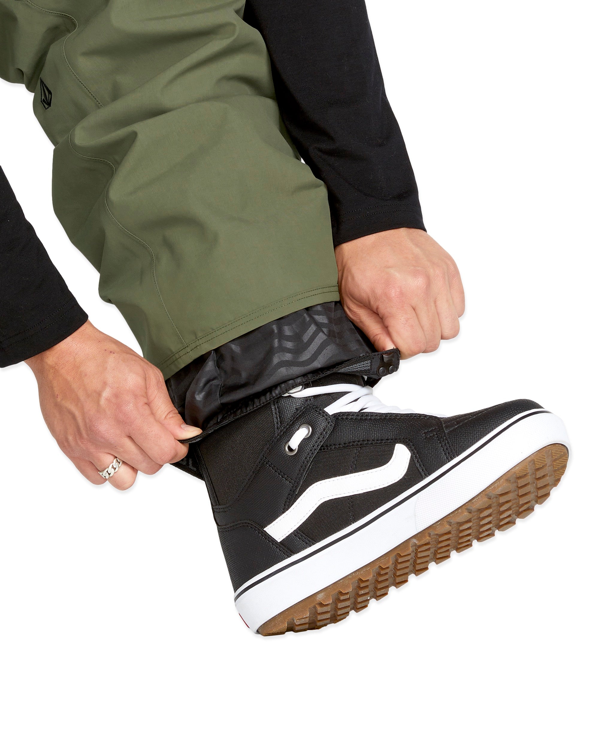Volcom Men's V.Co Sparta Bib Overall - A pair of olive green snow pants with a black zipper and white drawstring on the waistband.