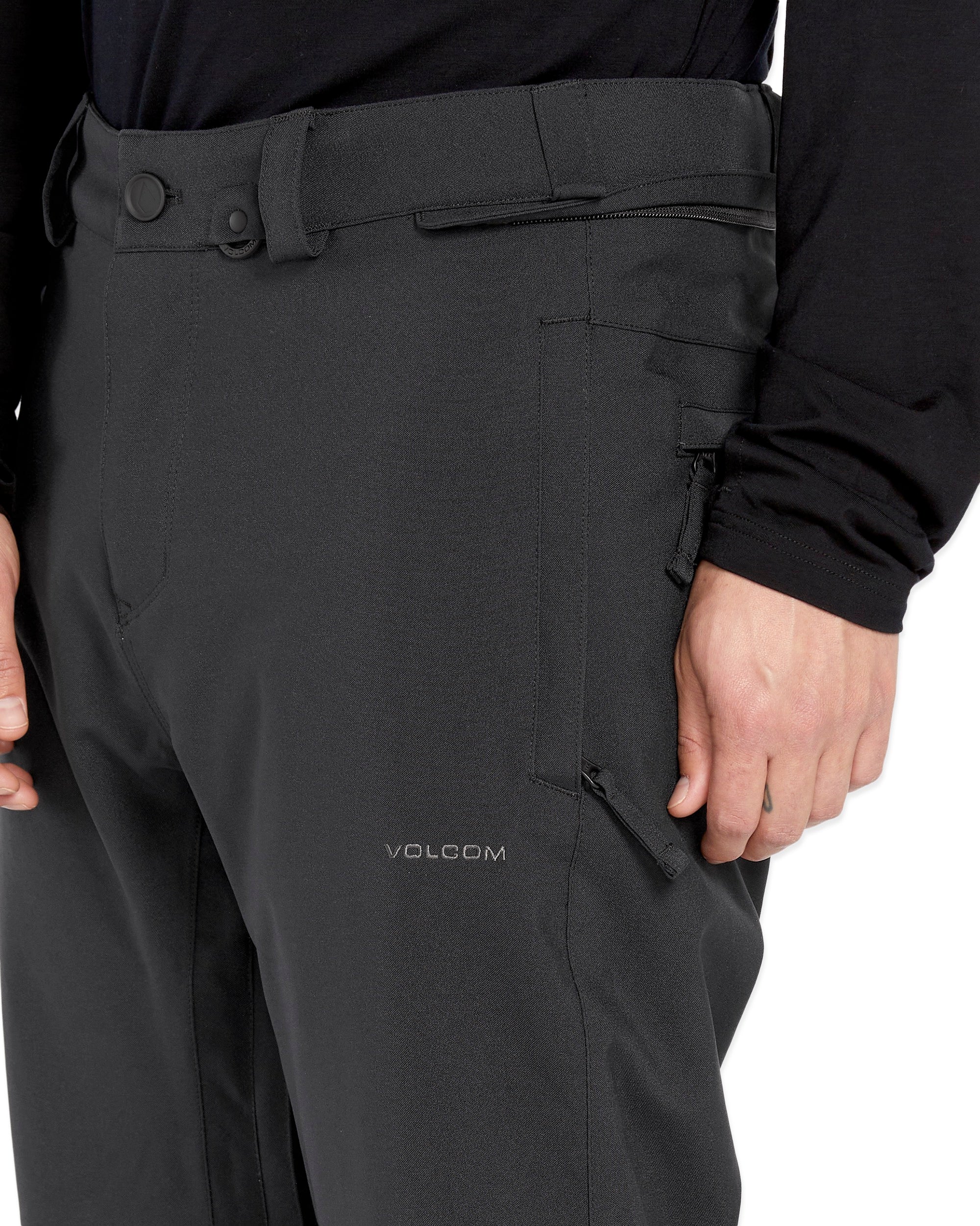 Volcom Men's Freakin' Snow Chino Pant 2025 - A pair of black snow pants with a zippered pocket on the side and a button fly.