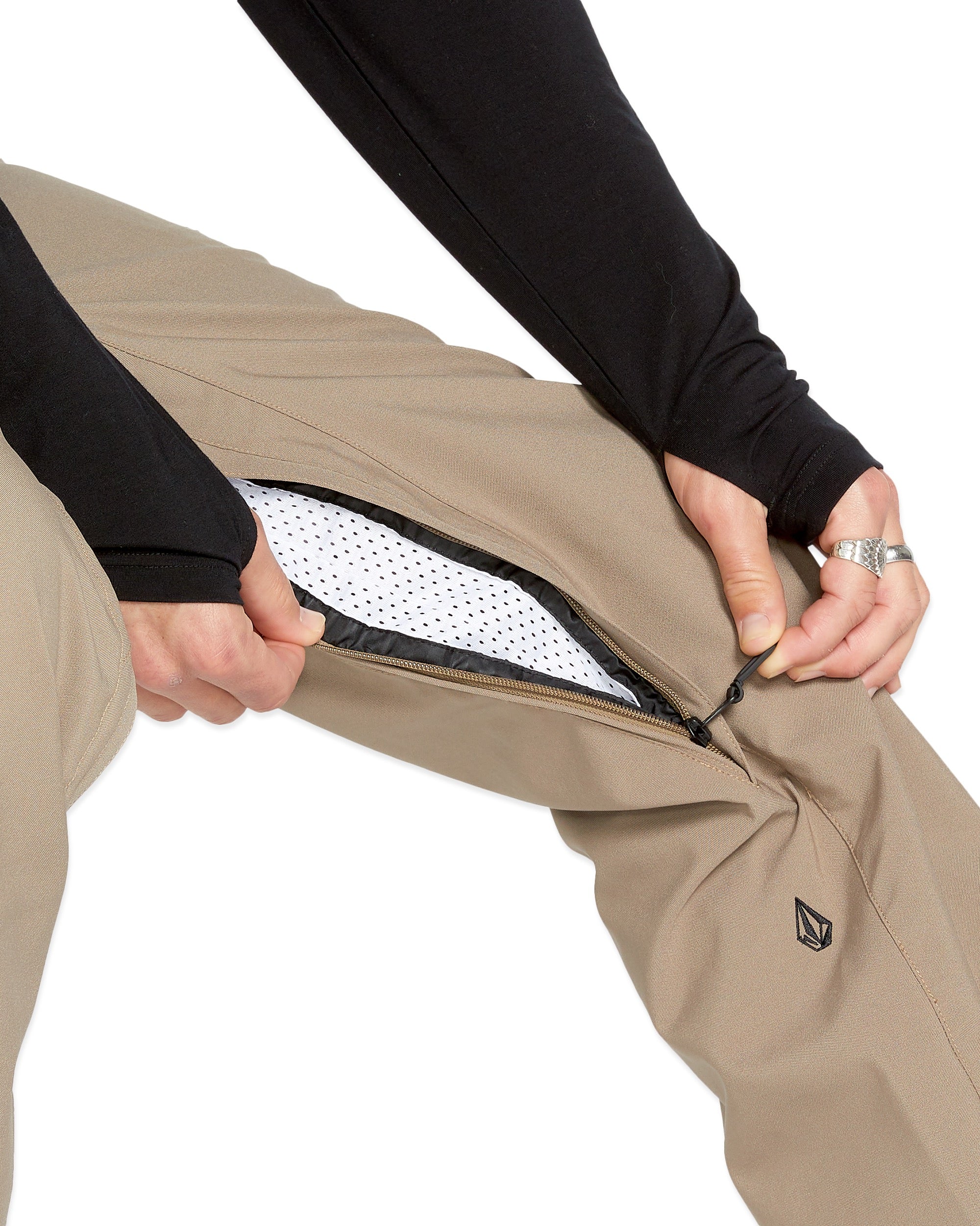 Volcom Men's Freakin' Snow Chino Pant - Beige snow pants with a zippered pocket on the side and a black logo patch on the left thigh.