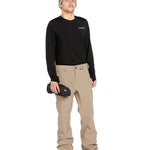 Volcom Men's Freakin' Snow Chino Pant - A pair of khaki-colored snow pants with a zippered pocket on the side and adjustable Velcro straps at the waist.