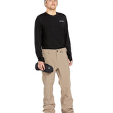 Volcom Men's Freakin' Snow Chino Pant - A pair of khaki-colored snow pants with a zippered pocket on the side and adjustable Velcro straps at the waist.