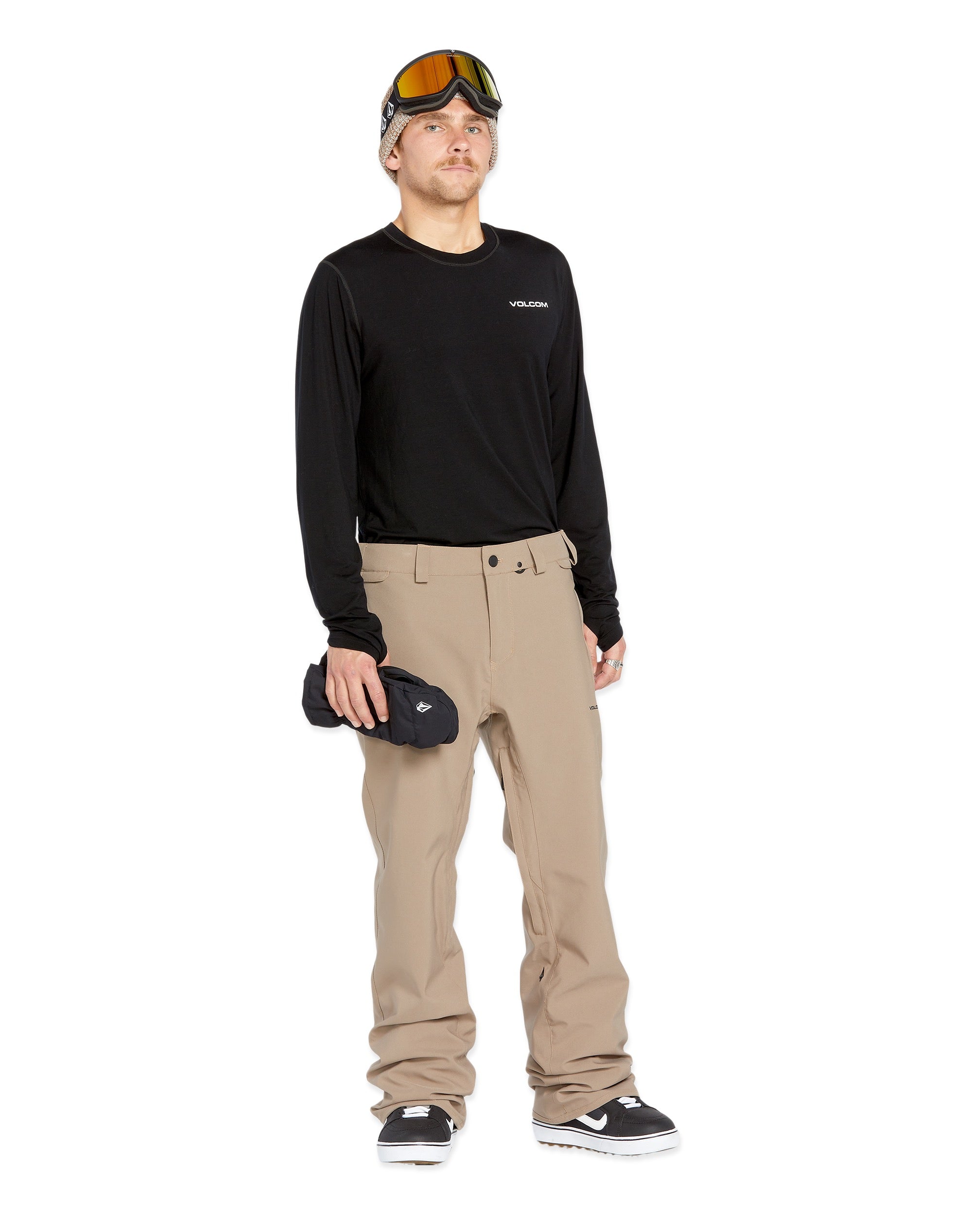 Volcom Men's Freakin' Snow Chino Pant - A pair of khaki-colored snow pants with a zippered pocket on the side and adjustable Velcro straps at the waist.