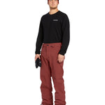 Volcom Men's Freakin' Snow Chino Pant - A pair of brown snow pants with a subtle pattern and two zippered pockets on the side.