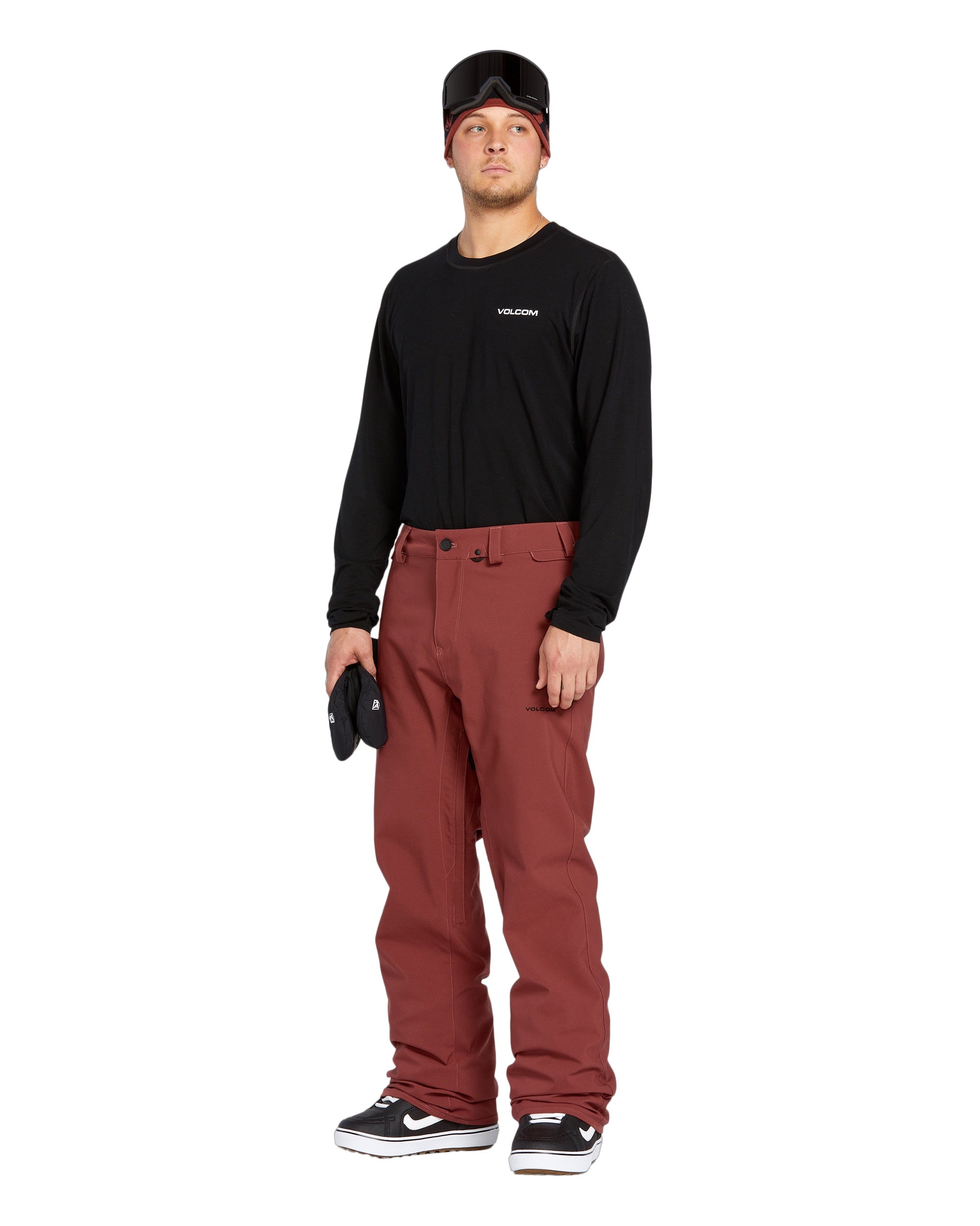 Volcom Men's Freakin' Snow Chino Pant - A pair of brown snow pants with a subtle pattern and two zippered pockets on the side.