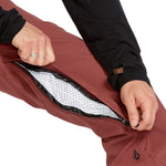 Volcom Men's Freakin' Snow Chino Pant - A pair of brown snow pants with a black zipper and logo on the left leg.