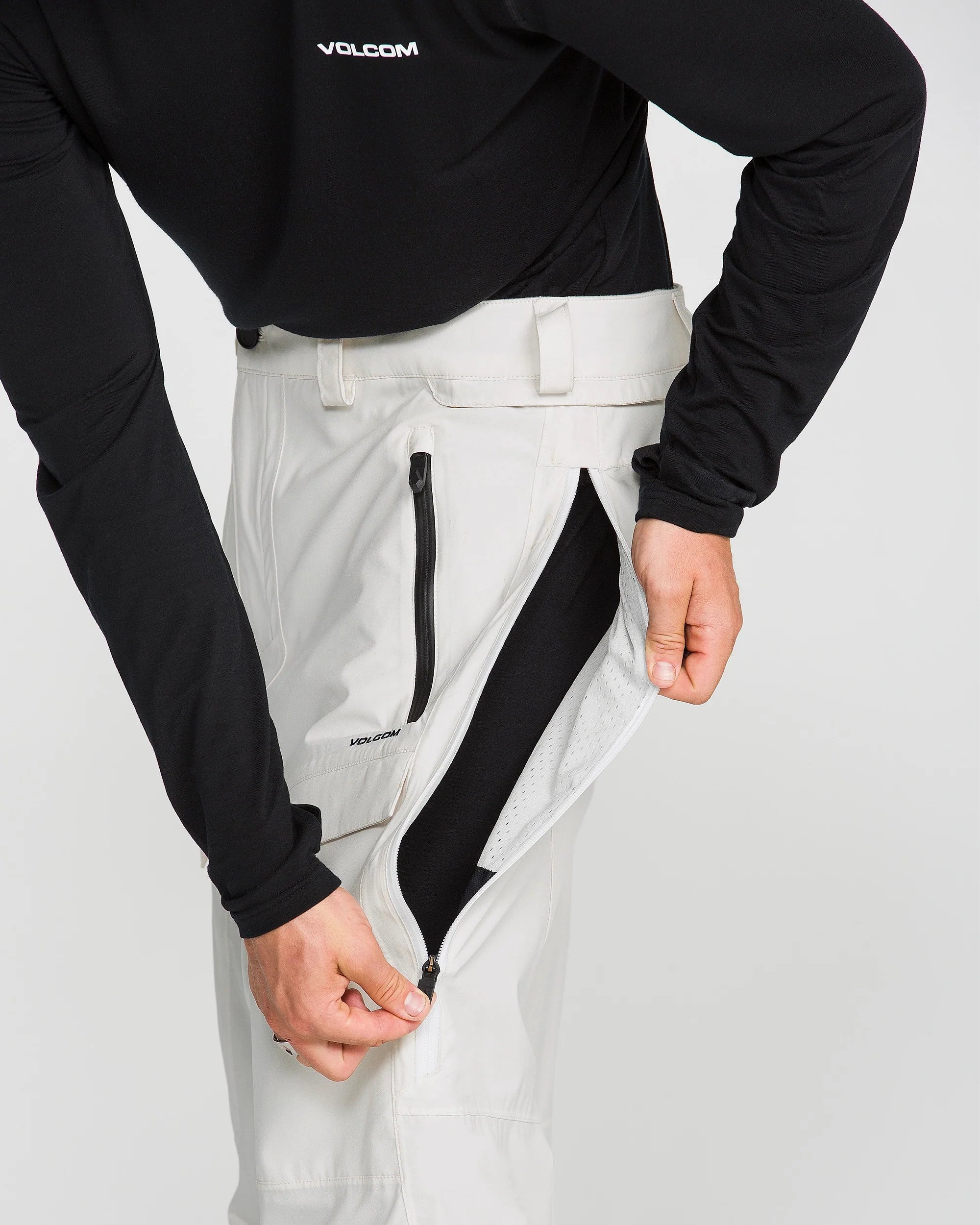 Off-white snowboard pants with front zip leg pocket and brushed interior lining.