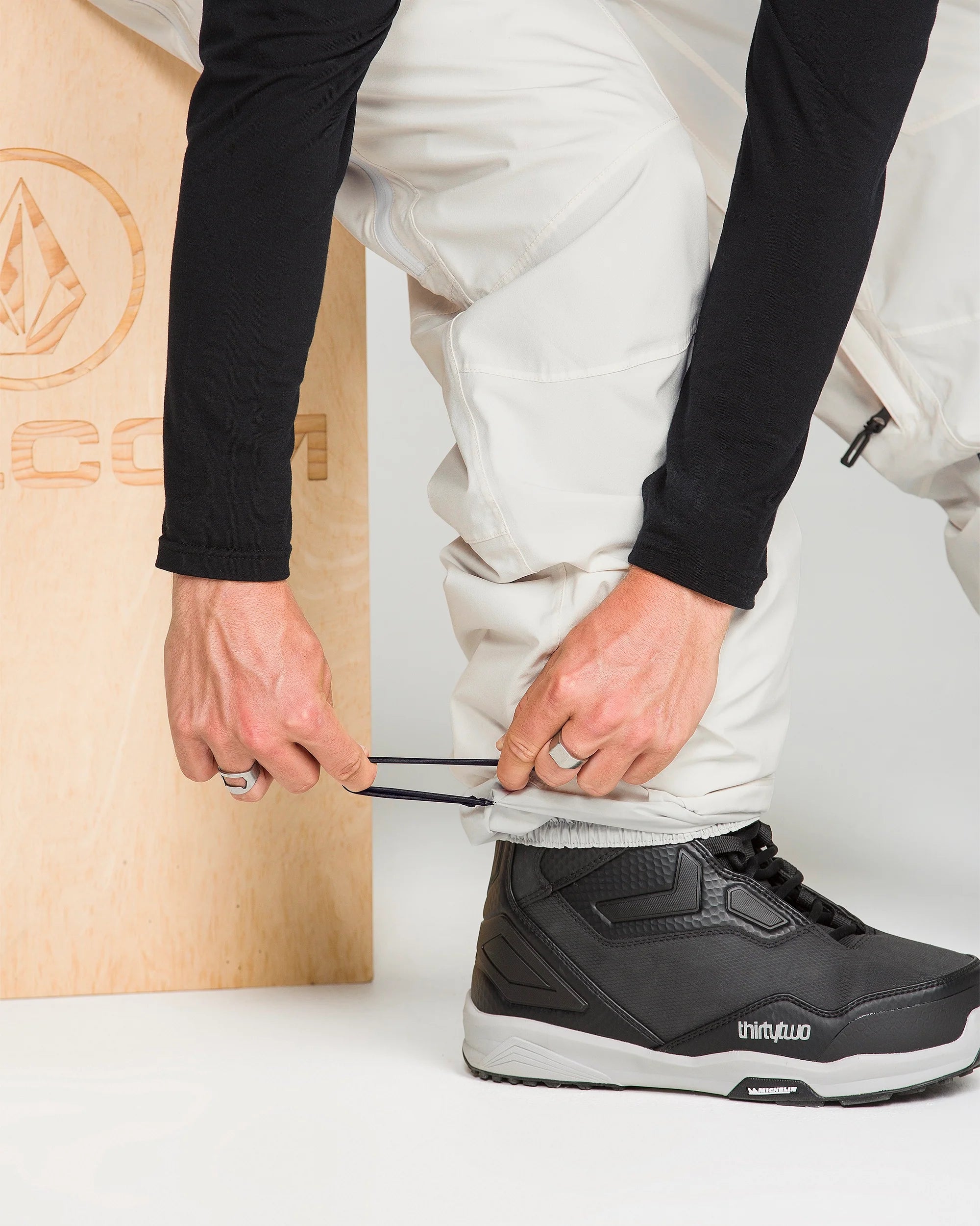 Off-white snowboard pants with tapered legs and adjustable cuffs.