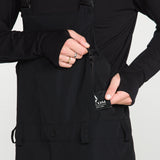 Black bib overall chest area with snap buttons, COM branding, and front zip pocket