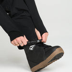 Black bib overall pant leg with cuff opening and logo patch at ankle