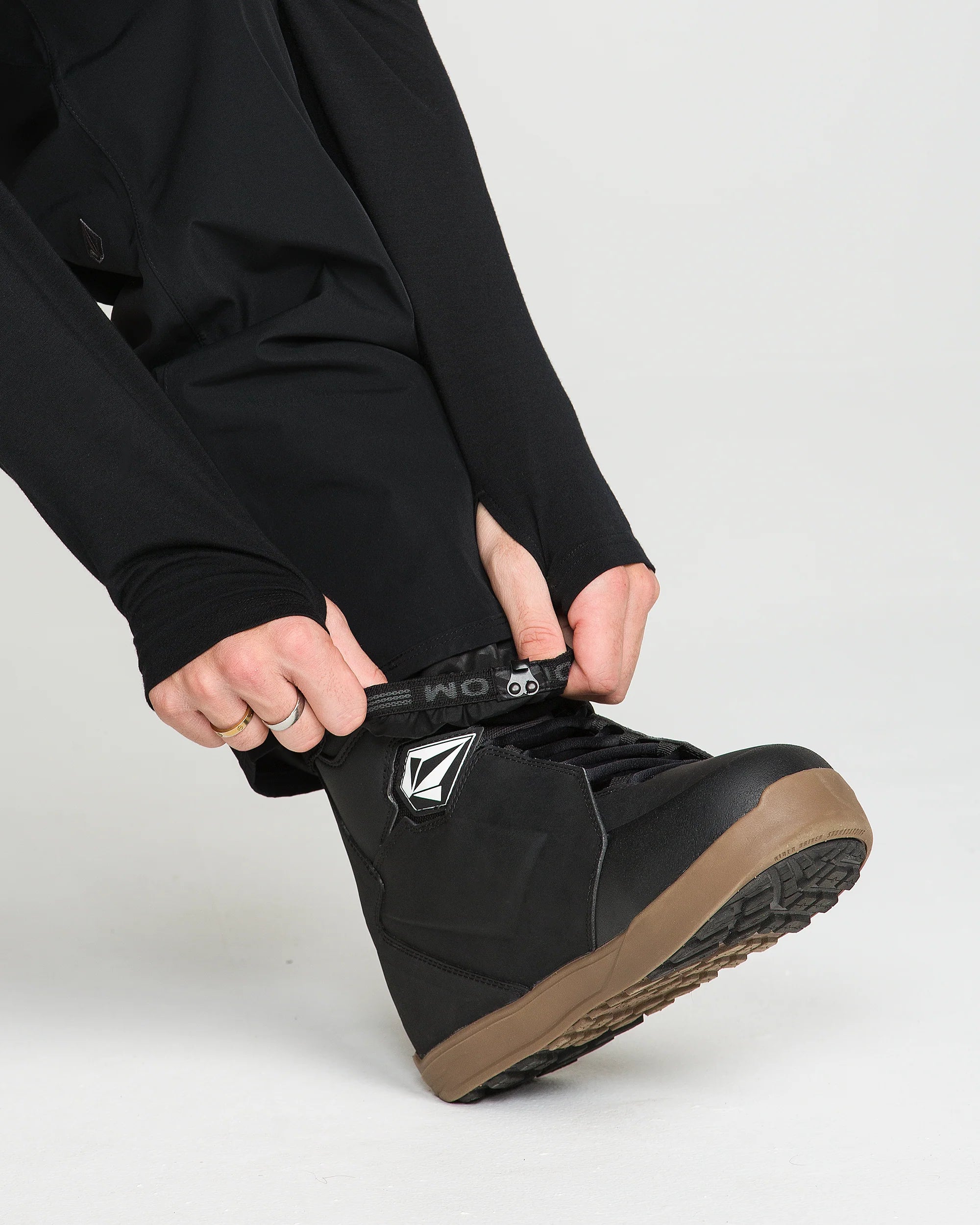 Black bib overall pant leg with cuff opening and logo patch at ankle