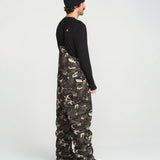 Camouflage bib overalls worn from side with black straps over the chest