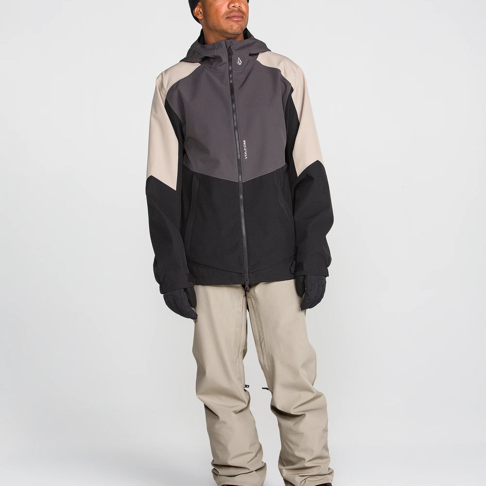 Beige and black snow chino pants worn by a model, full-body side view