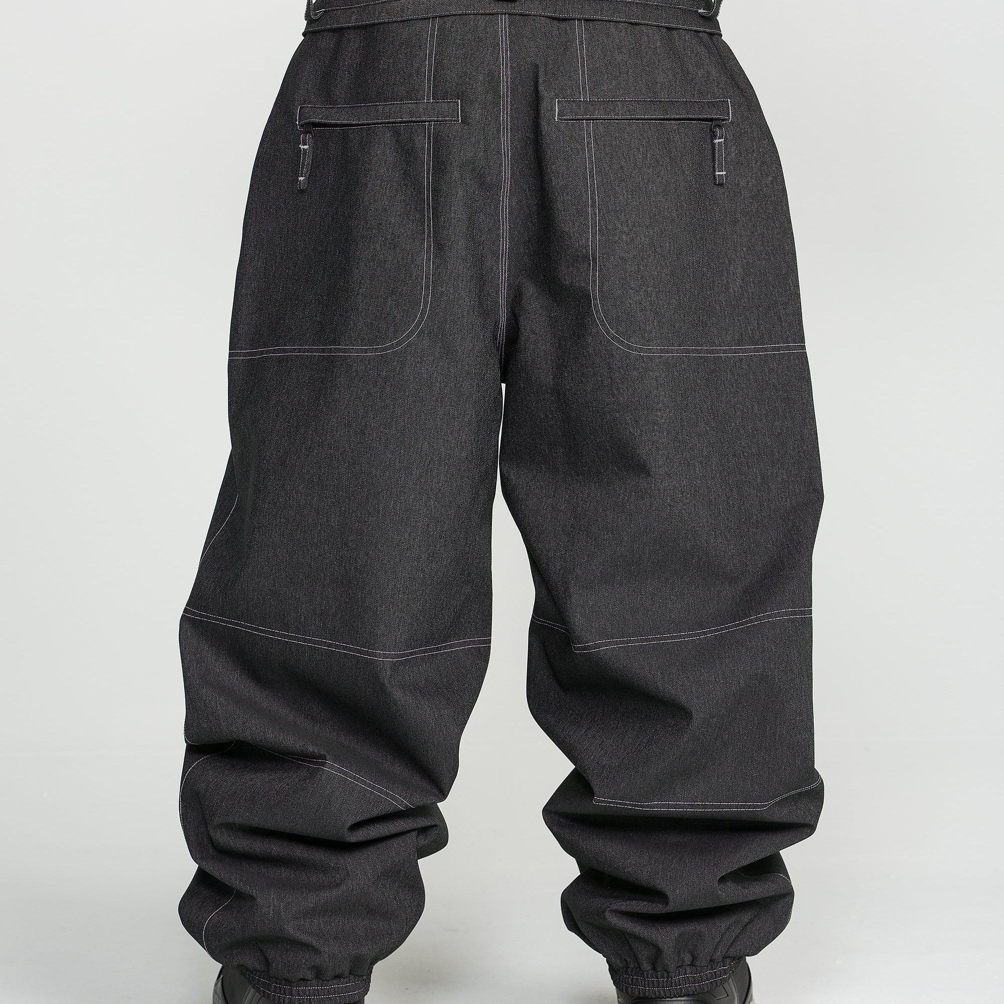 Black snow pants rear view with belt loops, stitched panels, and elastic cuffs