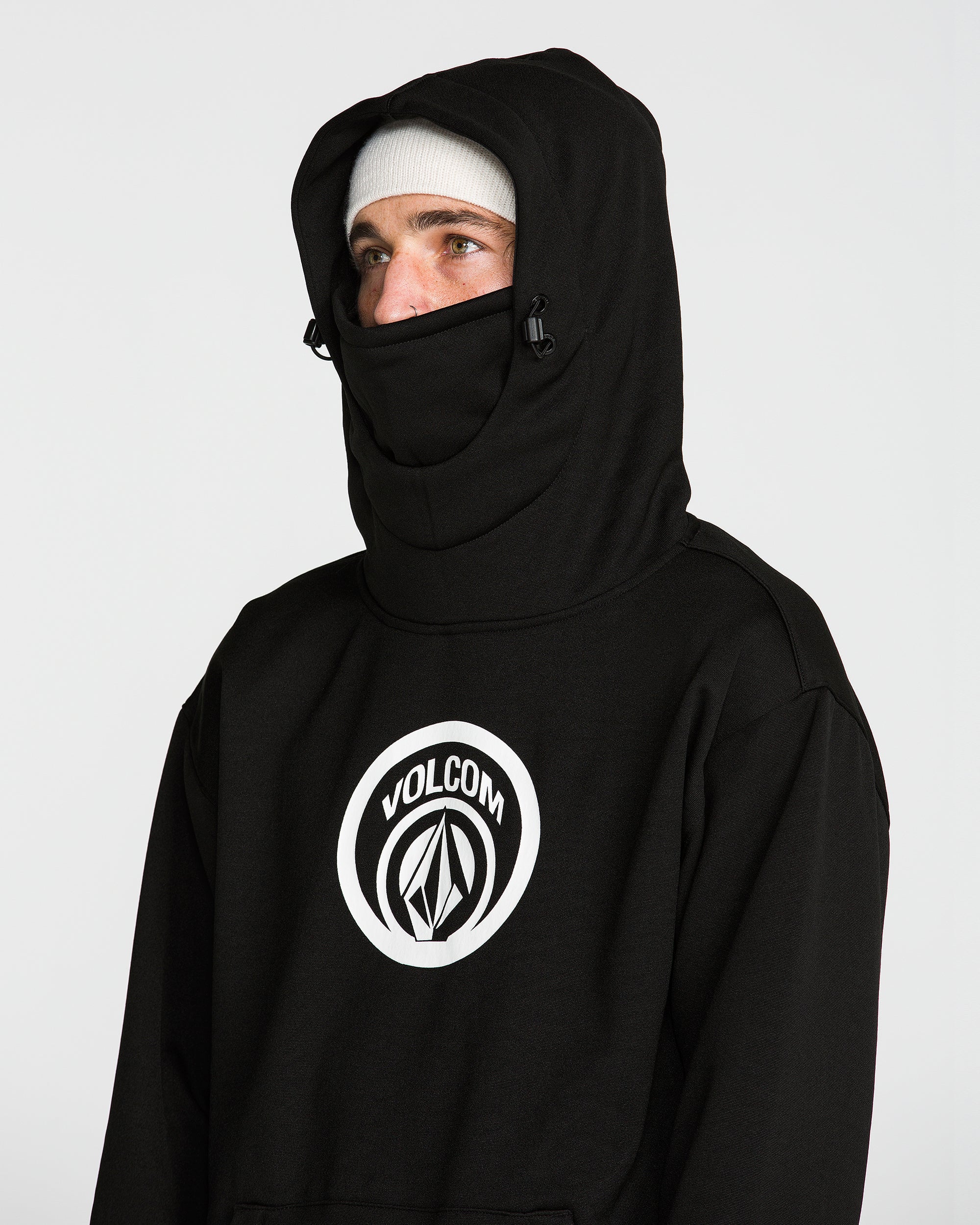 Black pullover hoodie with raised hood and face-covering panel, front chest logo