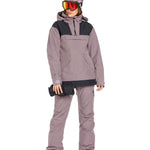 Volcom Women's Fern Insulated GORE-TEX Pullover - A woman wearing a mauve and black insulated pullover with a hood, holding a black glove in her right hand.