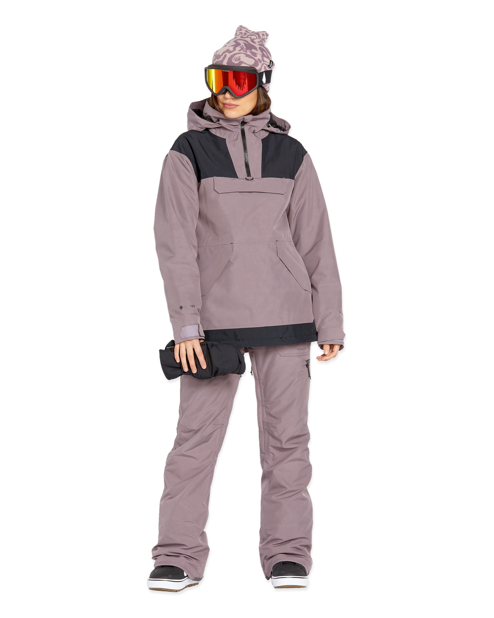 Volcom Women's Fern Insulated GORE-TEX Pullover - A woman wearing a mauve and black insulated pullover with a hood, holding a black glove in her right hand.