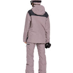 Volcom Women's Fern Insulated GORE-TEX Pullover - A woman wearing a dusty rose-colored jacket with black shoulder accents and a matching beanie, standing against a white background.
