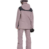 Volcom Women's Fern Insulated GORE-TEX Pullover - A woman wearing a dusty rose-colored jacket with black shoulder accents and a matching beanie, standing against a white background.