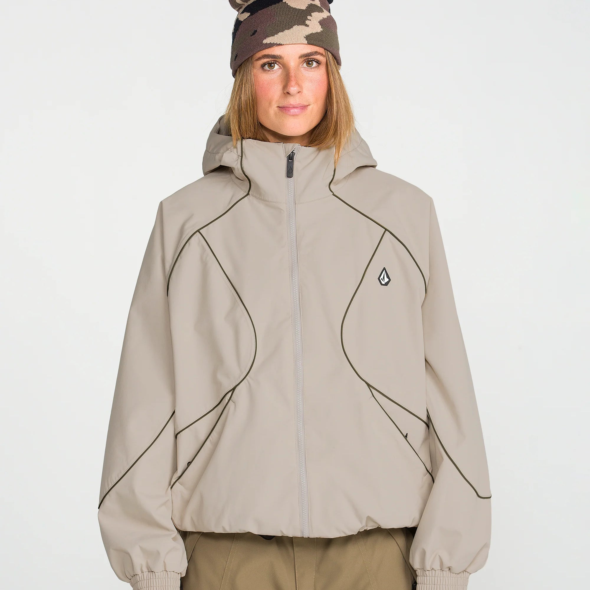 Women’s tan ski jacket with stand collar, full zip, and small chest logo detail.
