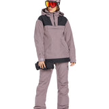Volcom Women's Knox Insulated GORE-TEX Pant - A woman wearing a matching purple ski jacket and pants, with a hood over her head, holding a black glove in her right hand.