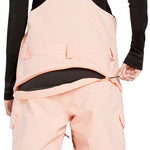 Volcom Women's Creston 3D Stretch Bib Overall - Light pink bib overalls with a black waistband and belt loops, featuring a zippered fly and two front pockets.