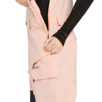 Volcom Women's Creston 3D Stretch Bib Overall - A light pink bib overall with a black zipper and two front pockets, featuring a "VOLCOM" logo on one pocket.