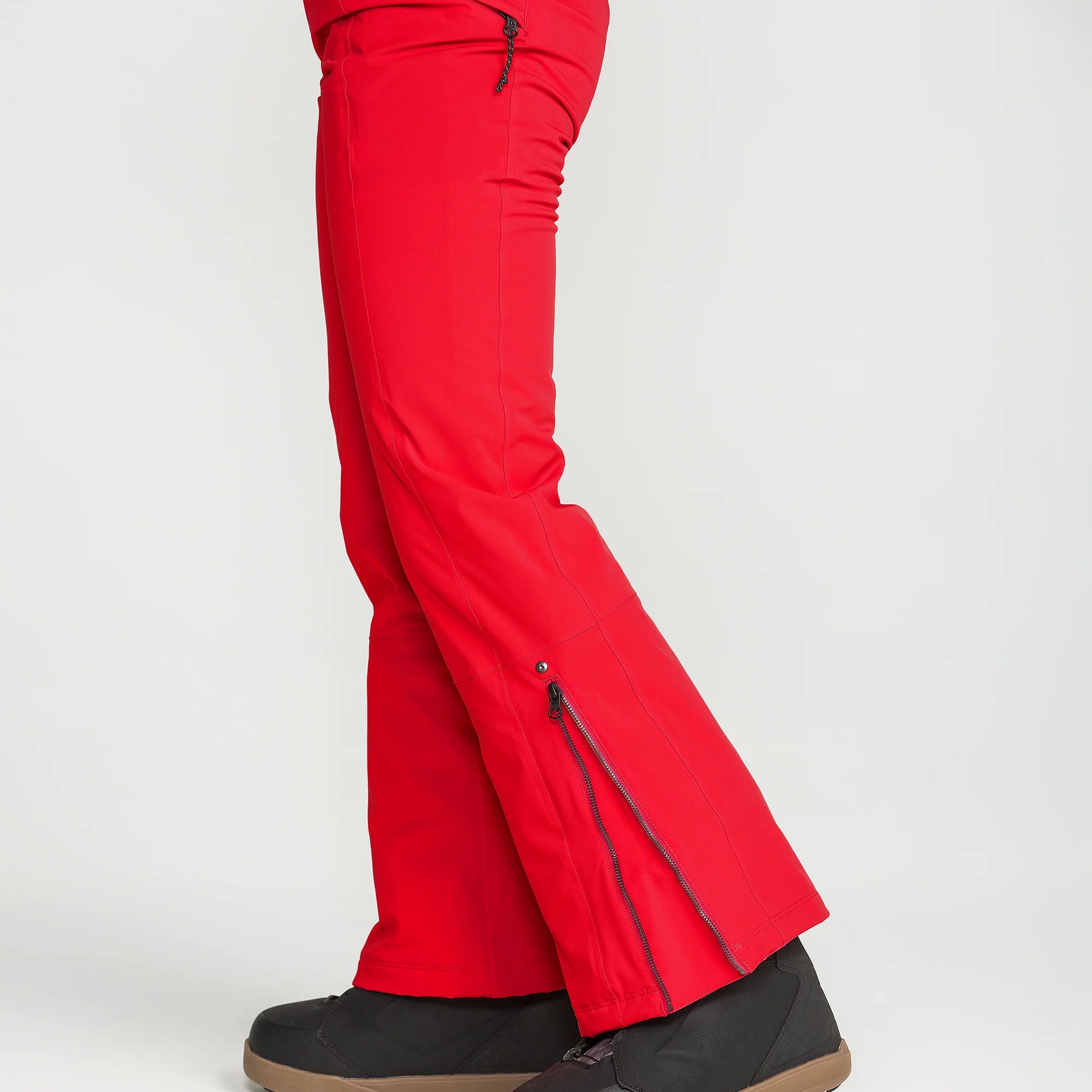 Red insulated ski pants with slanted thigh pocket and vented flare at the boot hem.