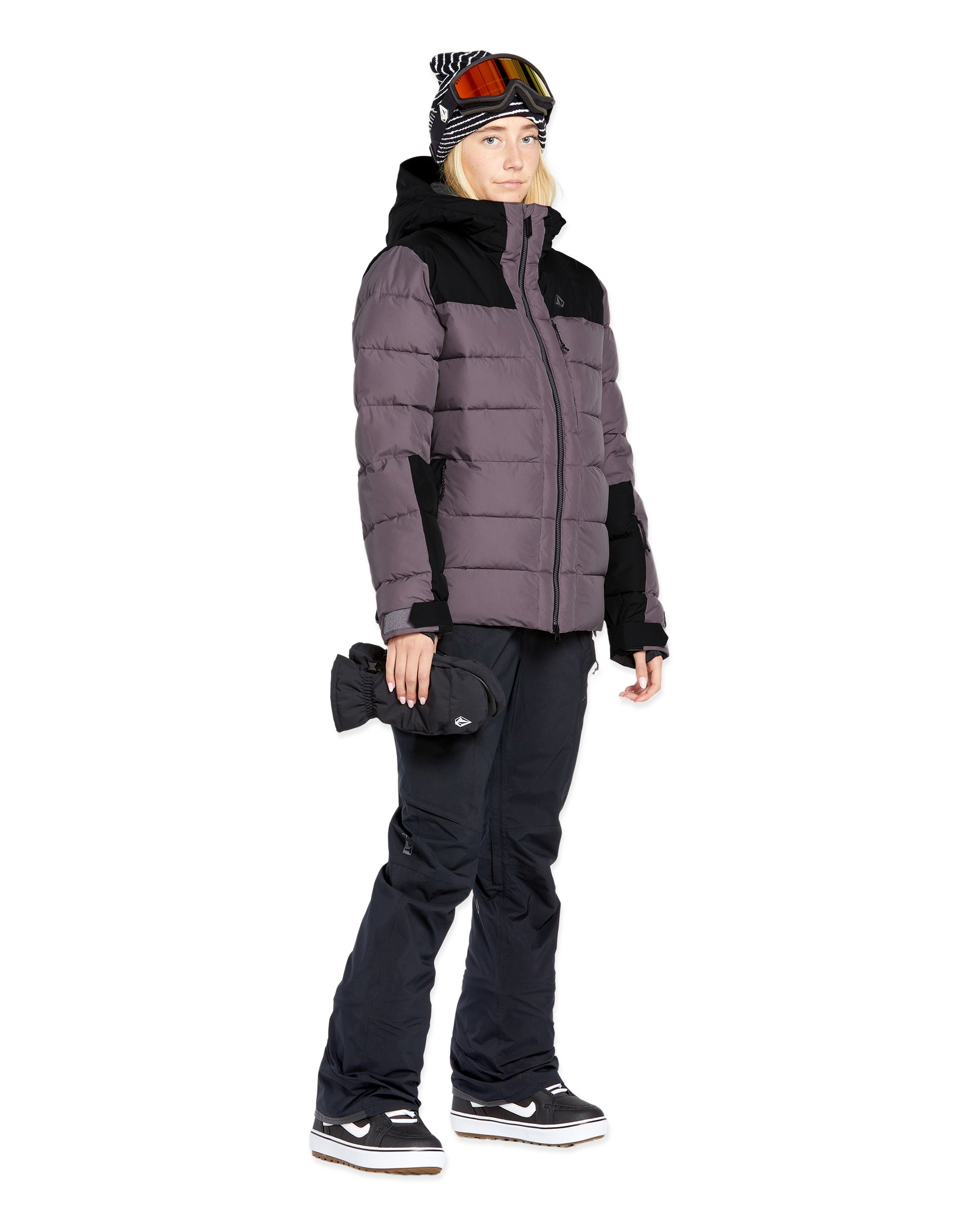 Volcom Women's Elm Stretch GORE-TEX Bib Overall - A woman wearing a black bib overall with a zippered fly and adjustable straps, paired with a matching black jacket and gloves.