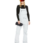 Volcom Women's Elm Stretch GORE-TEX Bib Overall - A pair of white snow pants with a black logo on the left thigh and a zippered pocket on the right thigh.