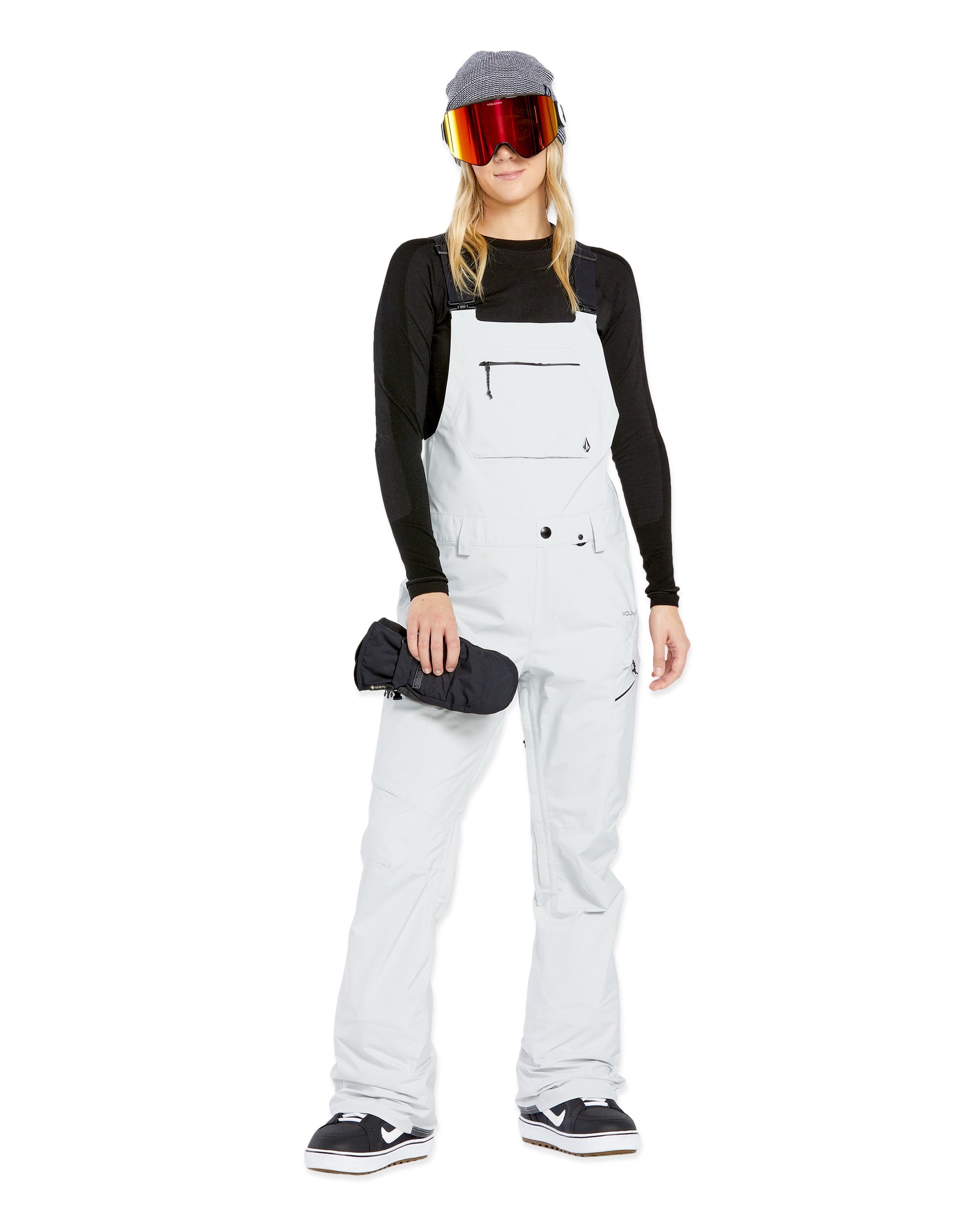 Volcom Women's Elm Stretch GORE-TEX Bib Overall - A pair of white snow pants with a black logo on the left thigh and a zippered pocket on the right thigh.