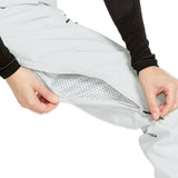 Volcom Women's Elm Stretch GORE-TEX Bib Overall - A woman wearing a white bib overall with black buttons and a black logo on the left leg, featuring a stretchy material and a GORE-TEX label.