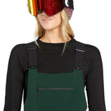 Volcom Women's Elm Stretch GORE-TEX Bib Overall - A pair of dark green snow pants with a zippered pocket on the thigh and adjustable straps at the waist.