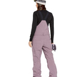 Volcom Women's Swift Bib Overall - A dusty rose bib overall with two front pockets and a zippered fly, featuring adjustable straps and a relaxed fit.