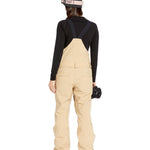 Volcom Women's Swift Bib Overall - Beige bib overalls with a black strap and buckle on the back, featuring two front pockets.