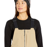 Volcom Women's Swift Bib Overall - A pair of khaki bib overalls with a zip front and adjustable straps.