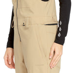 Volcom Women's Swift Bib Overall - A pair of khaki-colored bib overalls with a zippered fly and two front pockets.