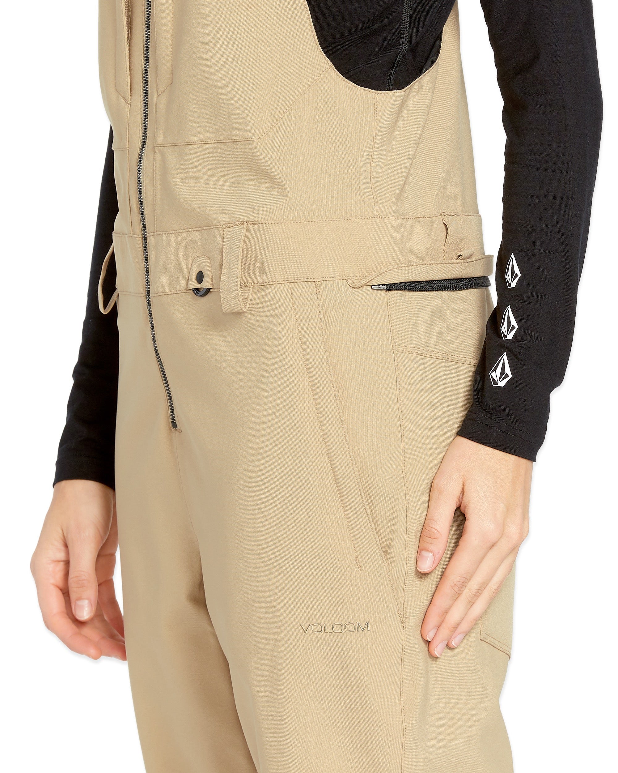 Volcom Women's Swift Bib Overall - A pair of khaki-colored bib overalls with a zippered fly and two front pockets.