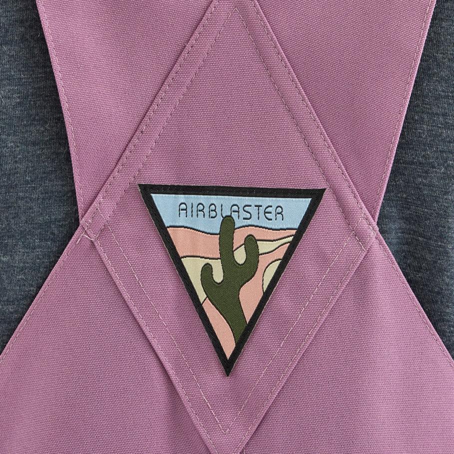 Airblaster Women's Hot Bib Shell 2025 - A pink snow bib shell with a white logo on the left chest and a black zipper running down the front.