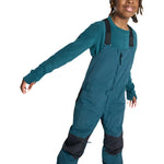Burton Junior's Skylar 2L Bib Pant 2025 - A pair of dark blue snow pants with a black strap and buckle on the waist, featuring a small logo on the left thigh.