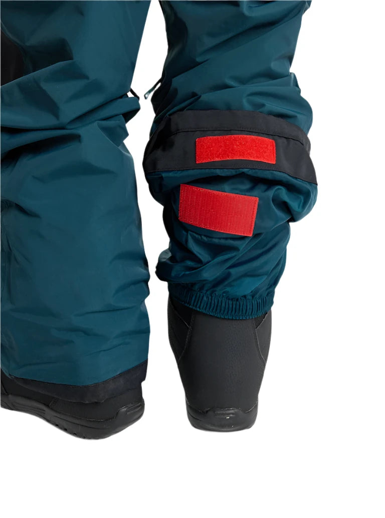 Burton Junior's Skylar 2L Bib Pant 2025 - A pair of dark green snow pants with a black waistband and belt loops, featuring two red patches on the left leg.