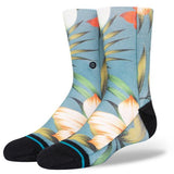 Stance Kid's Tropical Trollin Crew Sock 2023 - A pair of crew socks with a tropical design featuring palm trees and flamingos in shades of pink, green, yellow, and orange on a light blue background.