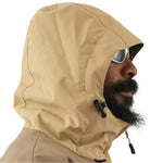 Airblaster Kook Shell Suit 2025 - A tan-colored, hooded jacket with a black zipper and two black drawstrings at the neck.