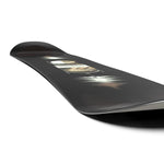 Salomon Pulse Snowboard 2025 - A black snowboard with a white logo on top and a blurry image of a person riding it in the background.