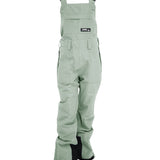Turbine Women's Longtrail Bib 2025 - A pair of light green bib overalls with a black logo patch on the front pocket.