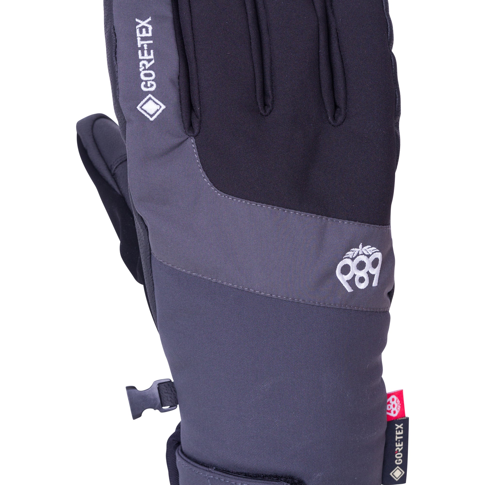 A black and gray glove with a red tag on the wrist strap, featuring the brand "GORE-TEX" and the model number "Linear Under Cuff Glove", as seen from the side view.