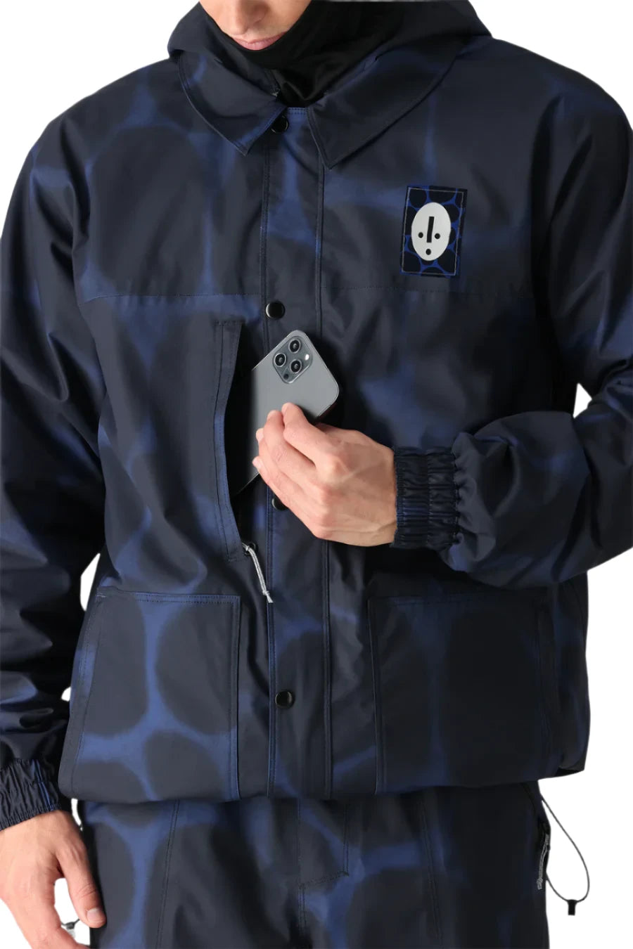 The 686 Dojo Shell Jacket 2025 has a blue and black pattern with a hood and a white logo on the left chest area.