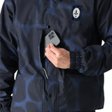 The 686 Dojo Shell Jacket 2025 has a blue and black pattern with a hood and a white logo on the left chest area.