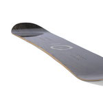 Arbor Women's Mantra Snowboard 2026 - A dark gray snowboard with a circular logo and white lettering on top, featuring a wood grain pattern on its bottom.
